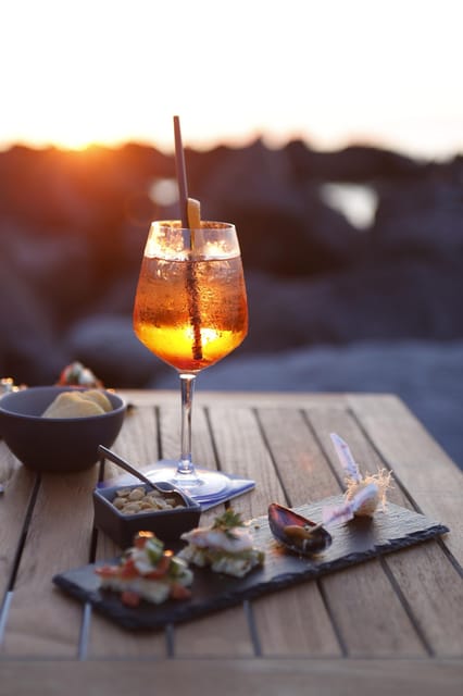 Italian aperitif at the sunset by the sea - Sunset aperitif in a private bay with a lighthouse view